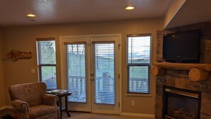 A living room with a fireplace, a television mounted above it, and a patterned armchair. - Eden/Powder Mountain/Snowbasin: mountain getaway, skiing, hiking, biking, golf (Eden)