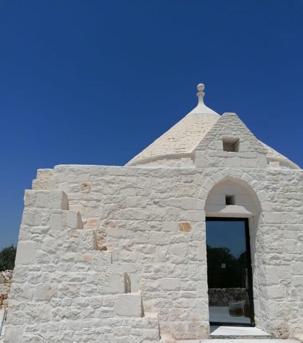 A small, white stone building with a pointed roof and an arched entrance.