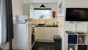 A compact kitchen with a microwave, oven, sink, and a small trash bin. - M & T Chalets , 2 bed chalet Hemsby. sleeps 6 (great yarmouth)