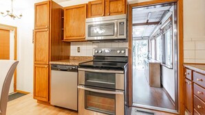A kitchen with wooden cabinets, a dishwasher, a microwave, an oven, and a window with a view. - Blissful Retreat w A trail behind & AC (Wisconsin Rapids)