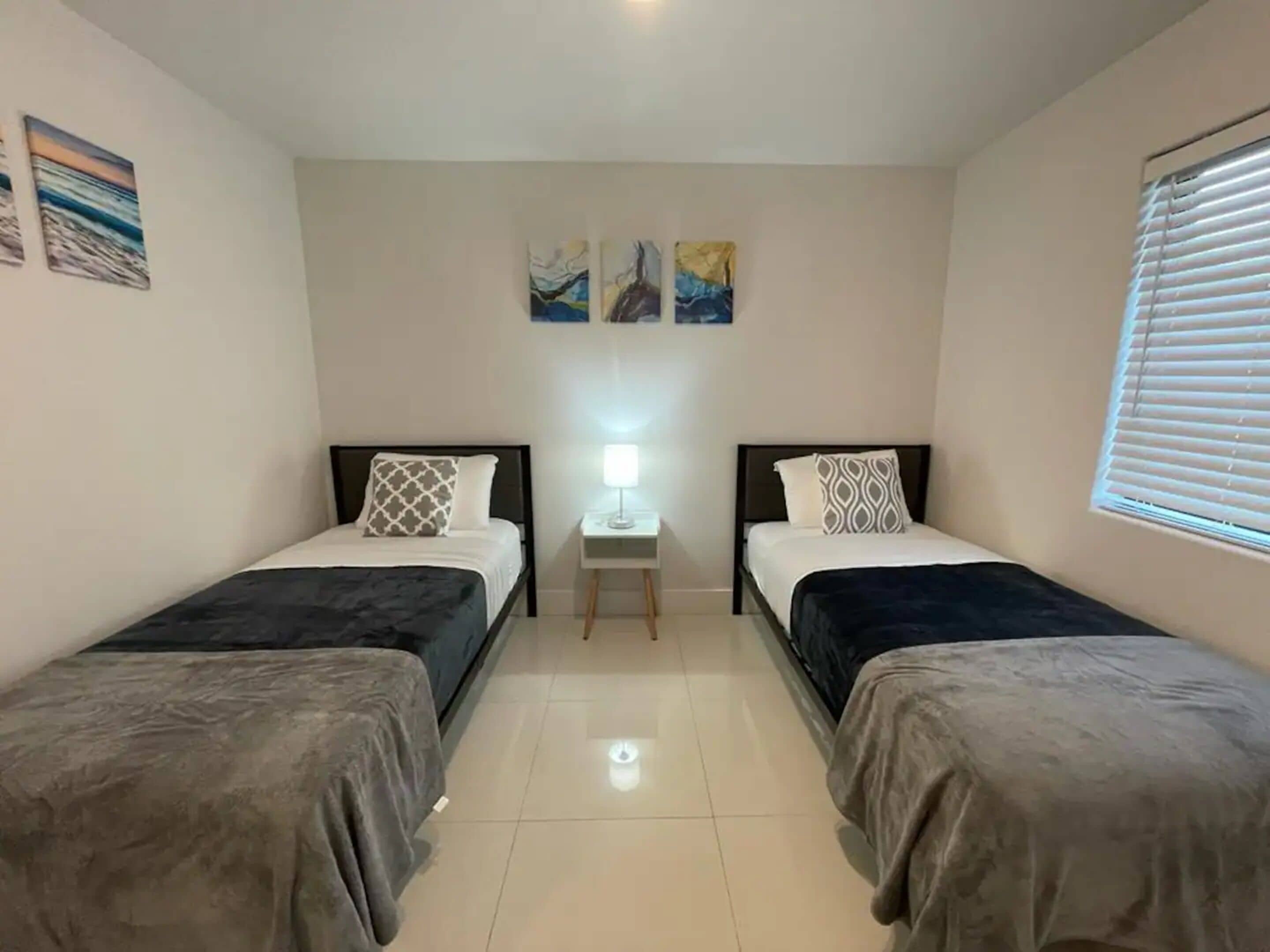 Een kamer met twee bedden, een klein tafeltje en kunstwerken aan de wanden.