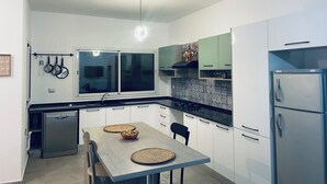 Cozinha moderna com armários brancos, forno embutido e geladeira de aço inoxidável.