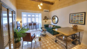 A cozy living room with a green sofa, a wooden coffee table, and a dining area with chairs and a table. - Traditional & chic 2 bedrooms in Valletta IMCD1-1 (Valletta)