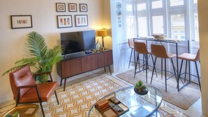 A living room with a TV, seating, a patterned floor, and a window with a view. - Traditional & chic 2 bedrooms in Valletta IMCD1-1 (Valletta)