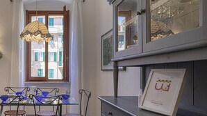 Uma sala de jantar com uma mesa e cadeiras, uma janela com cortinas e um armário com portas de vidro.