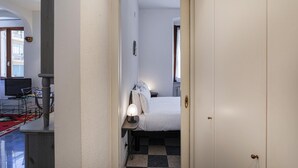 Quarto de hotel com cama, luminária de cabeceira e vista para o exterior.
