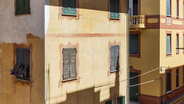 Um edifício de vários andares com varandas e persianas, apresentando um estilo arquitetônico clássico.