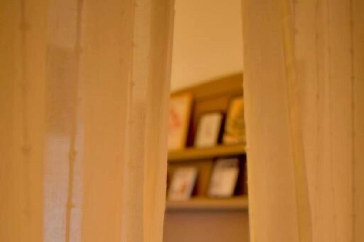 Une chambre avec un lit, une table de chevet et une étagère où sont posés des cadres avec des photos.