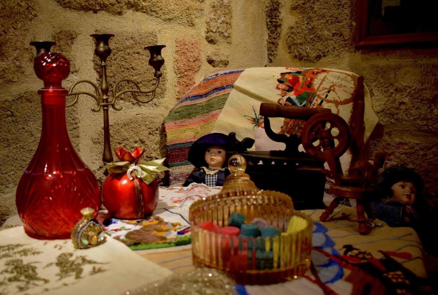 A table with various objects including a red vase, a doll, and a patterned cloth.