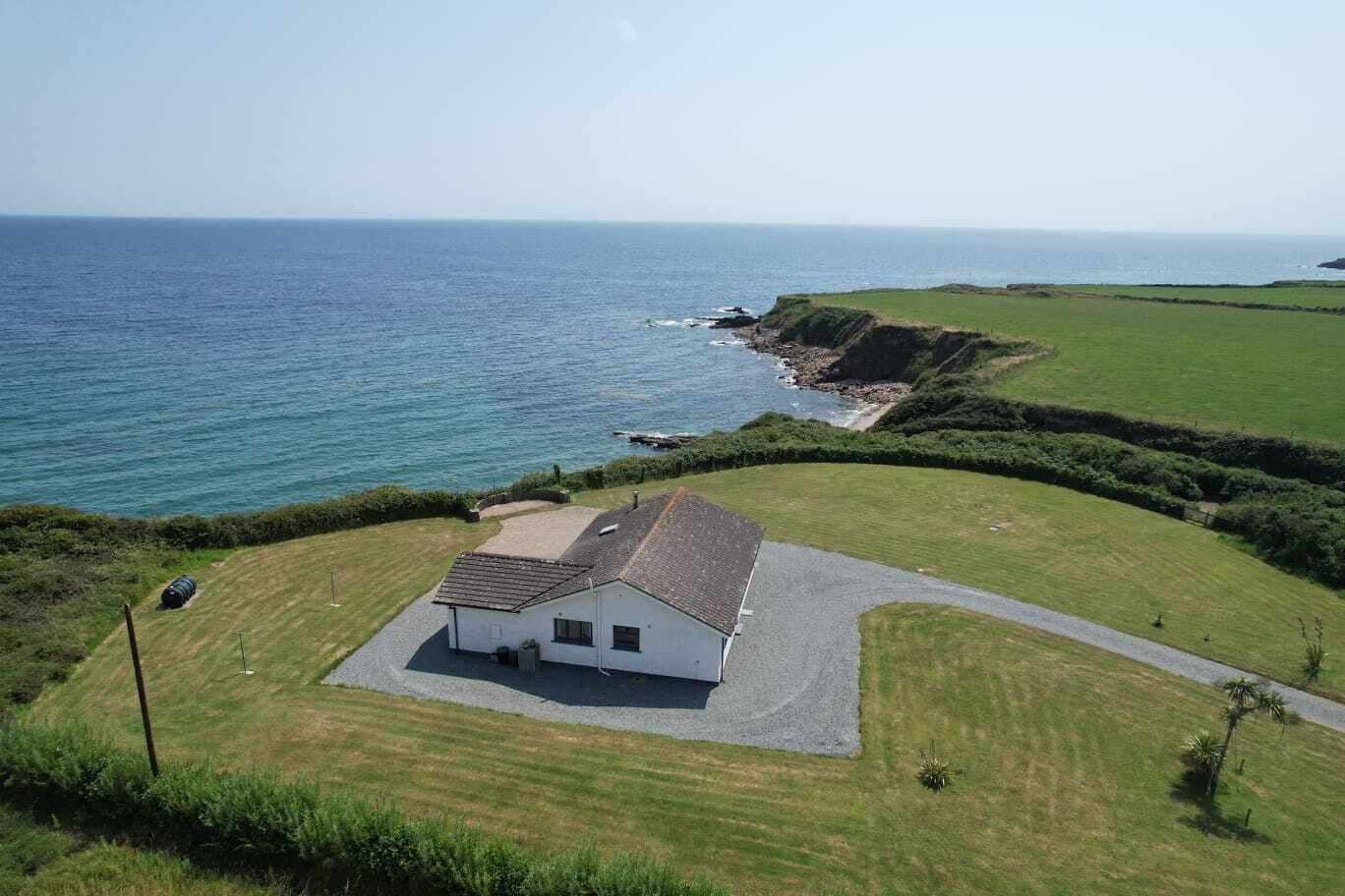 A coastal property with a single-story house, a driveway, and a lawn.