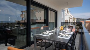 A dining area with a table set for two, chairs, and a view of the city through large windows. - Apartment Summer Breeze Okrug Gornji (Okrug)