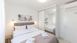 A neatly arranged bedroom with a large bed, a bedside table, a mirror, and a door. - Apartment Summer Breeze Okrug Gornji (Okrug)