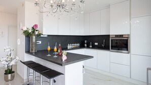 A modern kitchen with a central island, stainless steel appliances, and a chandelier. - Apartment Summer Breeze Okrug Gornji (Okrug)
