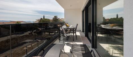 Un balcon aménagé avec une table à manger, des chaises et un canapé.