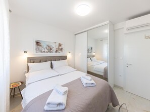 A hotel room with a bed, a bedside table, a mirror, and a door. - Apartment Summer Breeze Okrug Gornji (Okrug)