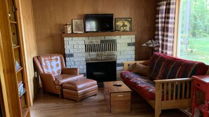 A cozy living room with a fireplace, leather armchair, and a colorful sofa. - This is what “Up North” feels like! (Lewiston)