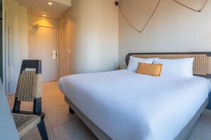 Ein Hotelzimmer mit einem großen Bett, einem Sessel und einer Tür.