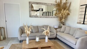 A living room with a grey sofa, two white vases with dried plants, a wooden coffee table, and a mirror on the wall. - Splendid villa with swimming pool & sea view (Roquebrune-sur-Argens)
