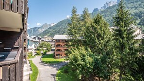 A building with a balcony, a green lawn, and a mountain backdrop.