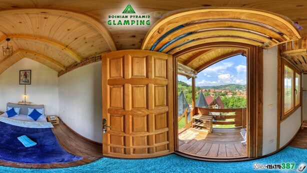 A room with a curved ceiling, a wooden door leading to an outdoor deck, and a view of the countryside. - Blue bungalow Bosnian pyramid glamping (Visoko)