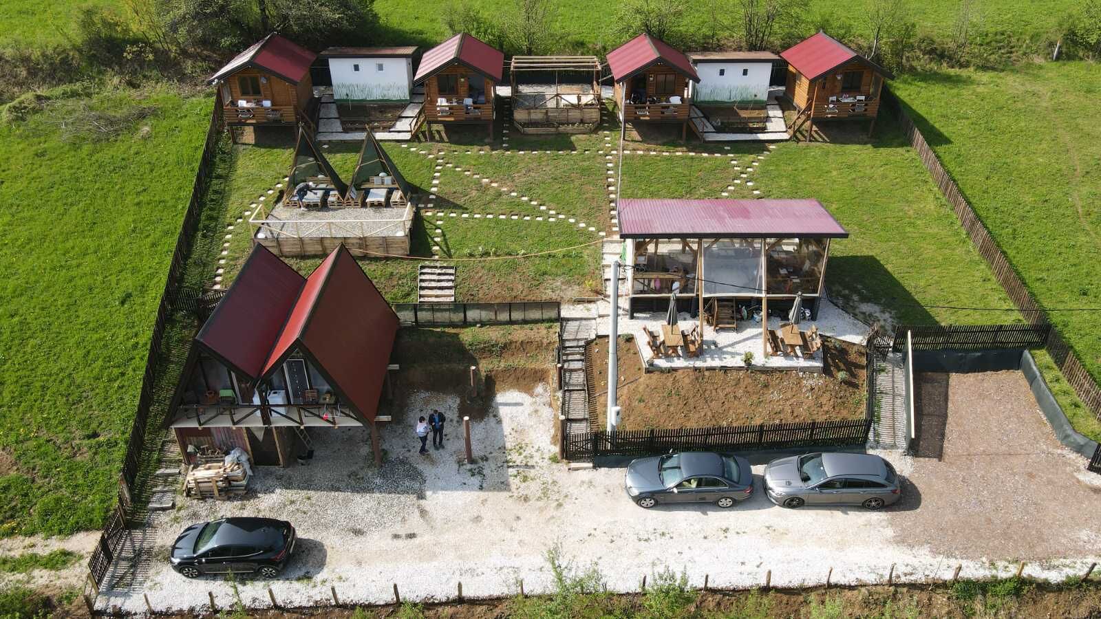 A lodge with multiple cabins, a central building with a red roof, and a gravel parking area.
