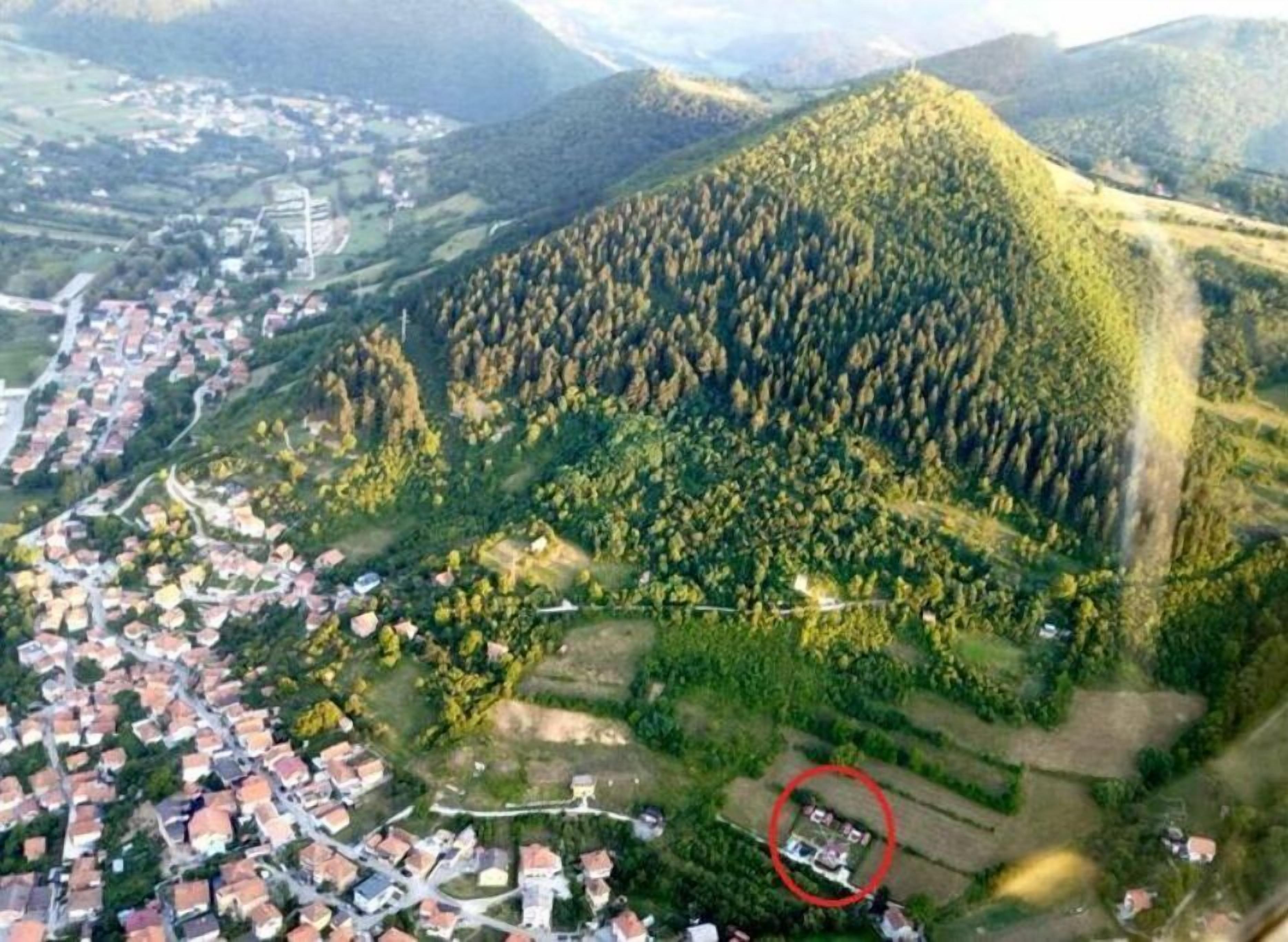 Vista aerea di una zona montuosa con un quartiere residenziale alla base.