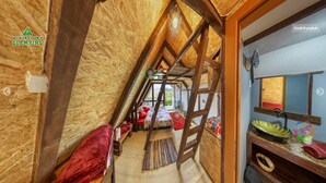 A narrow attic bedroom with a wooden ceiling, a small window, and a view of the outdoors. - Red bungalow Bosnian pyramid glamping (Visoko)