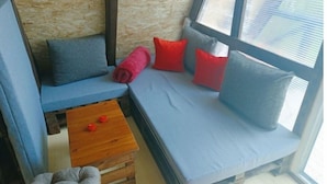 A cozy room with a blue sofa, red and grey cushions, a wooden coffee table, and a grey armchair. - Red bungalow Bosnian pyramid glamping (Visoko)