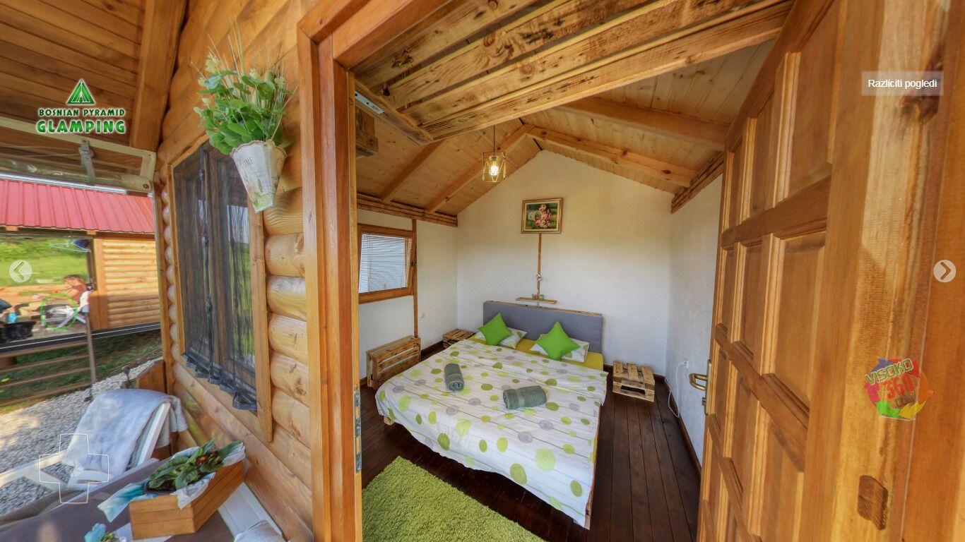 A cozy log cabin bedroom with a bed, a window, and a wooden ceiling.