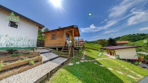 A wooden cabin with a small deck and a staircase leading to a balcony. - Green bungalow Bosnian pyramid glamping (Visoko)
