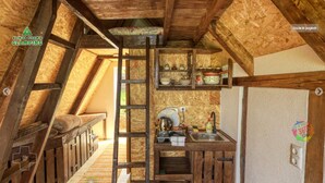 A rustic kitchen with wooden beams, a ladder, and a sink.