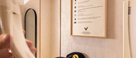 A framed sign with text and a black hat with a gold emblem on a wall.
