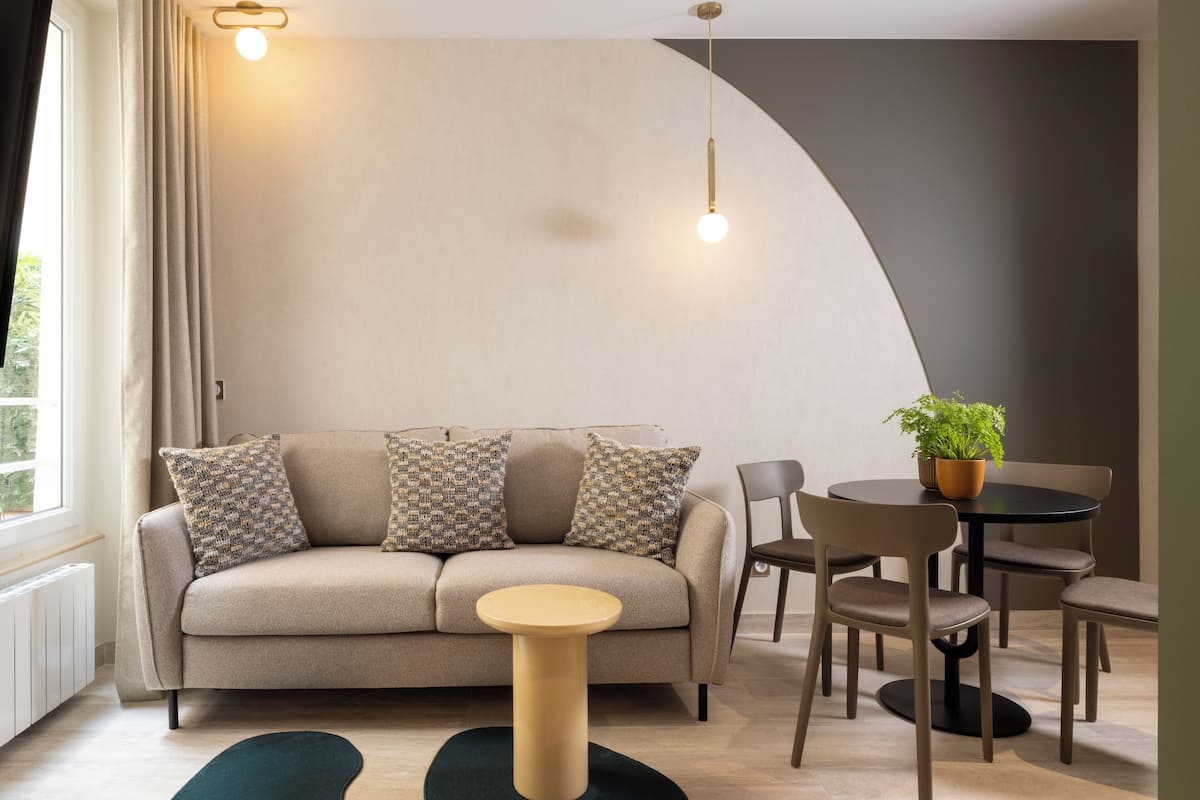 A modern living room with a sofa, chairs, a small table, and a potted plant.