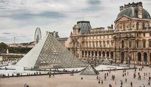 Suuri avoin aukio, jonka taustalla kohoavat Louvren museo ja Louvren pyramidi.