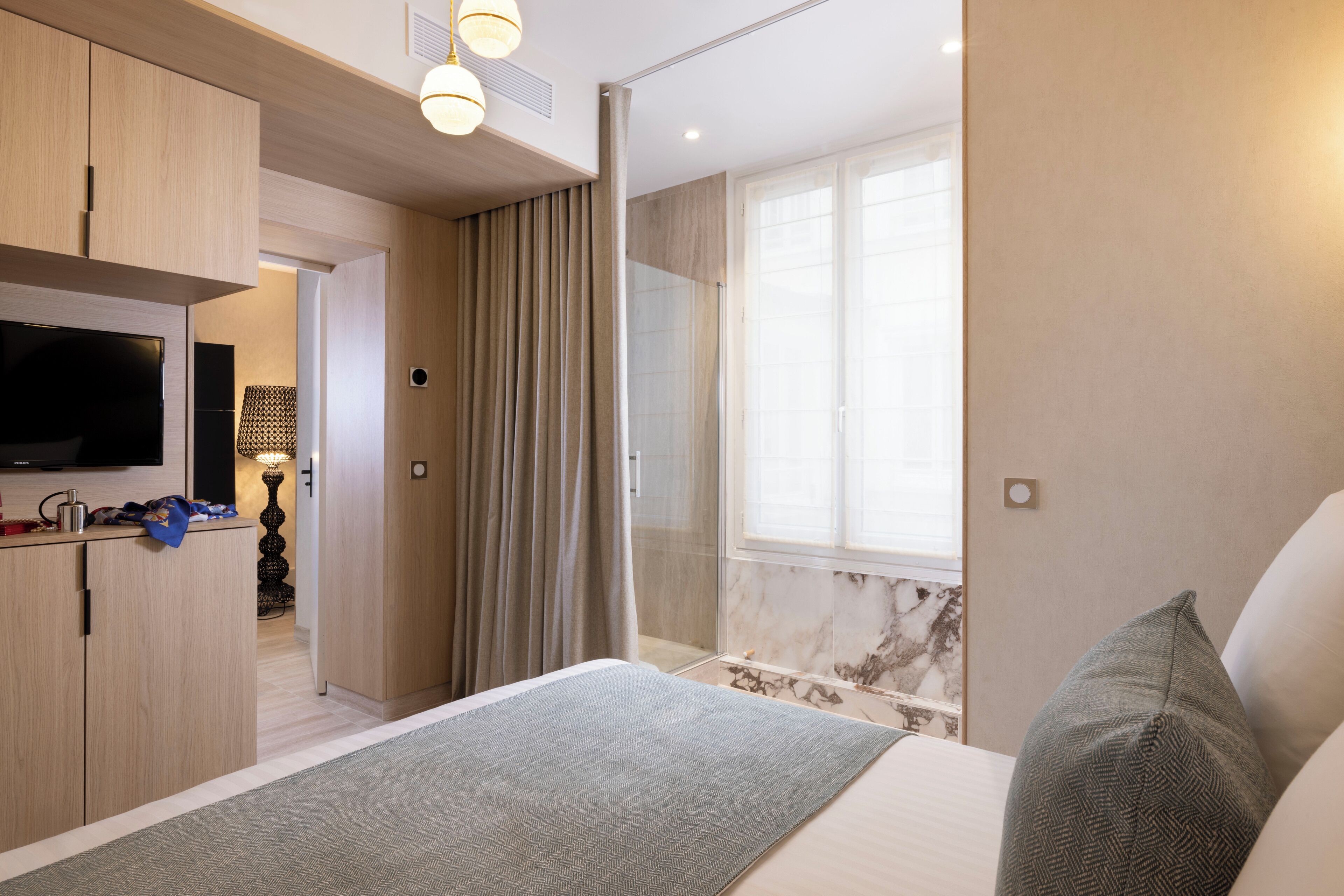 A modern bedroom with a bed, a TV, a shower, and a bathroom.