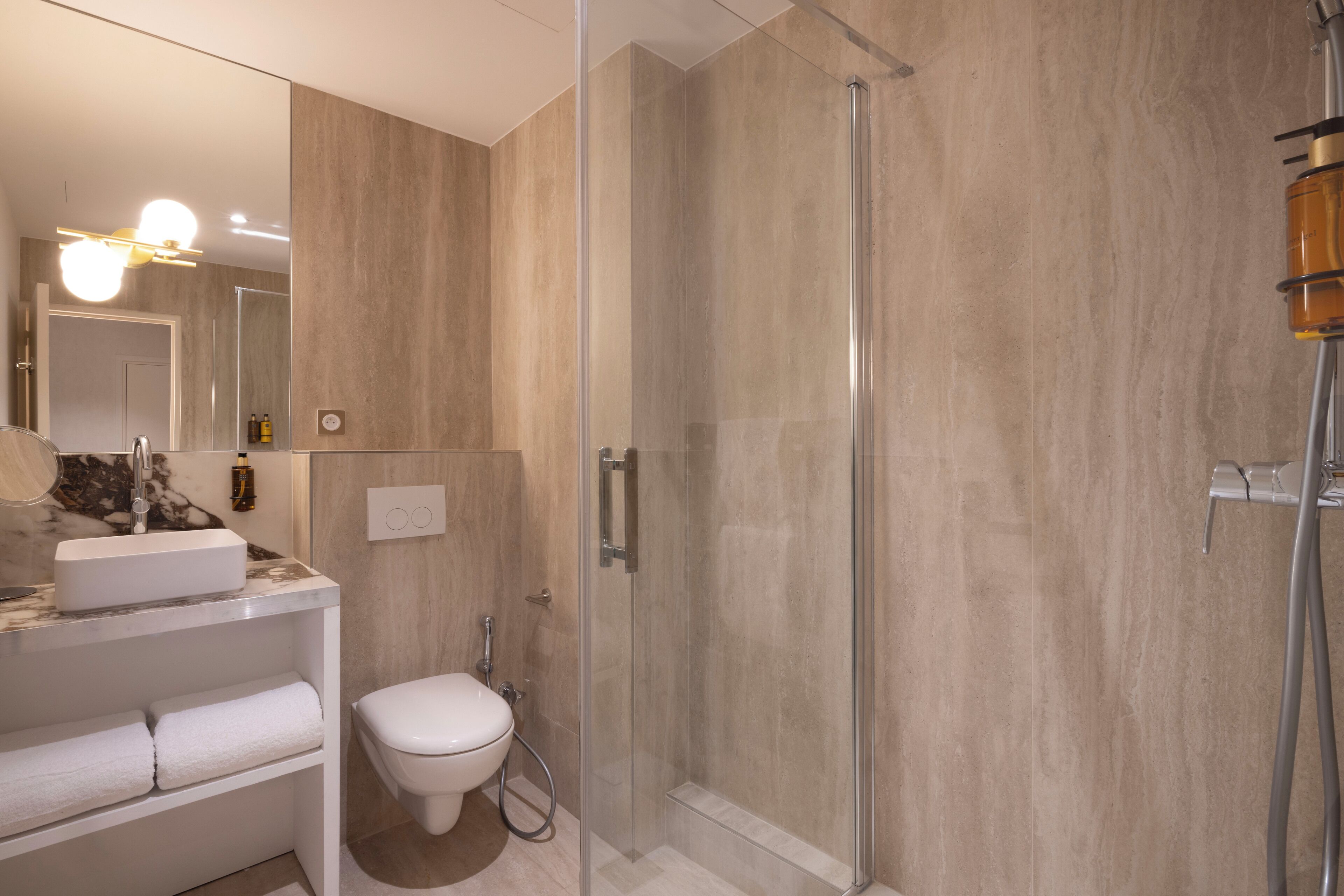 A modern bathroom with a glass-enclosed shower, a marble sink, and a toilet.