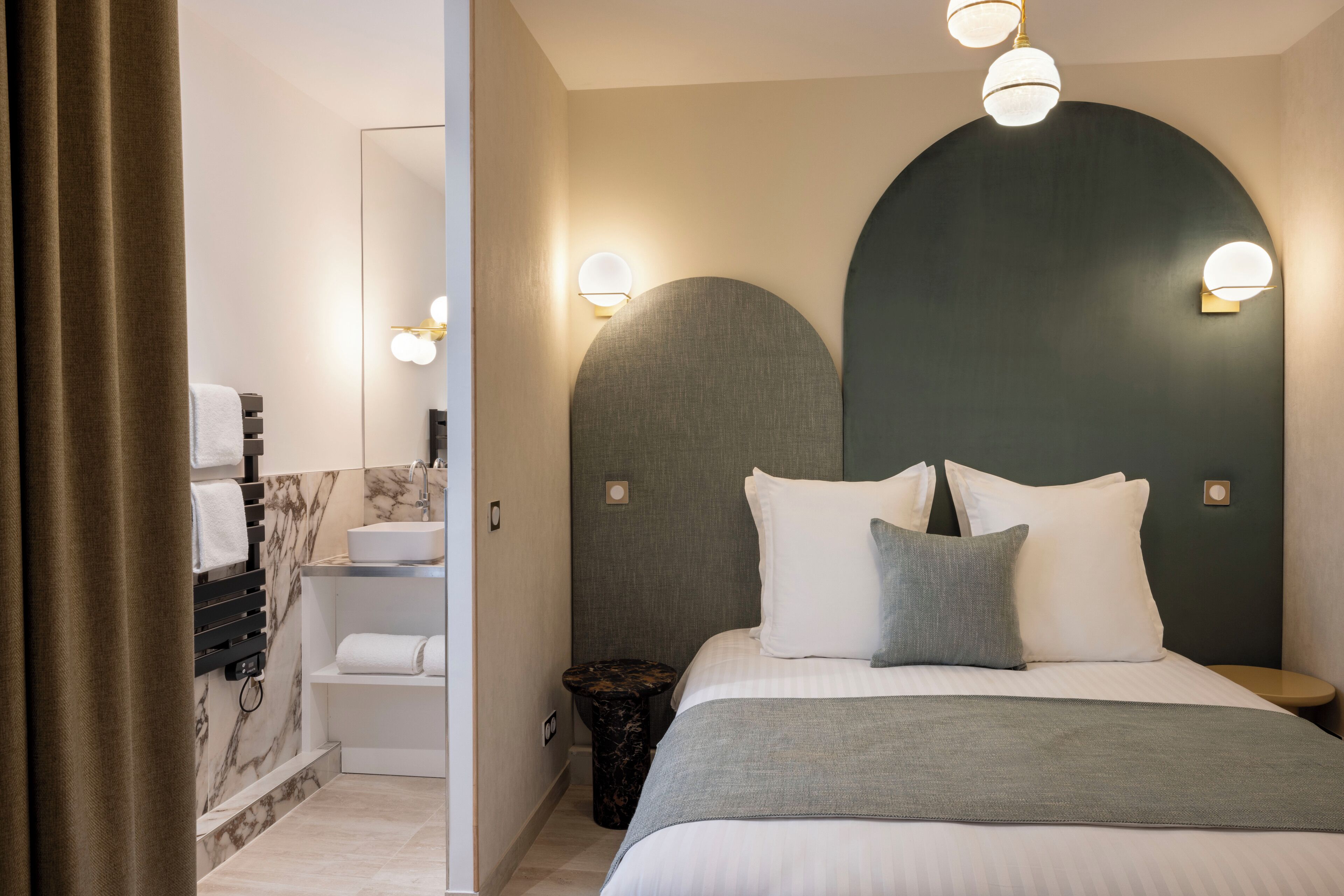 A modern bedroom with a large bed, a bathroom with a marble vanity, and a unique wall design.