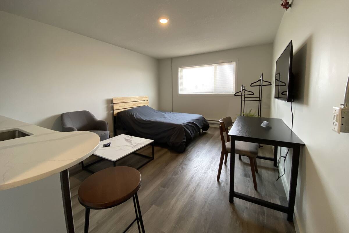 A compact room with a bed, a desk, a chair, and a TV.