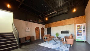 Un espacio de oficina moderno con una escalera, sofás de cuero, una mesa de centro y una máquina expendedora.