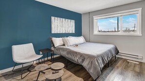 Un dormitorio con cama, una silla, una mesita y una ventana con vistas.