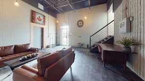 Un vestíbulo amplio con sofás de cuero, una mesa de madera y una escalera.