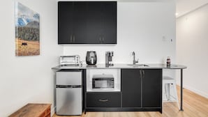 Una cocina moderna con gabinetes negros, microondas integrado, cafetera y tostadora.