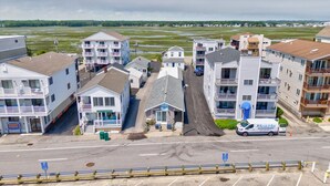 Un hotel fronte spiaggia con diversi piani, un'area parcheggio e una strada che conduce alla spiaggia.