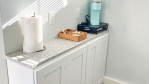 Una cucina con mobili bianchi, un piano di lavoro in granito, una macchina per il caffè e una candela.