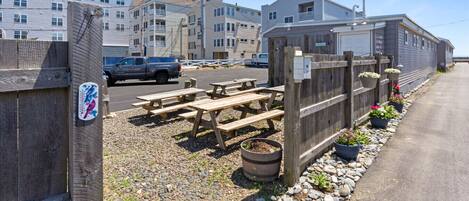 A parking area with picnic tables and potted plants.