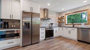 A modern kitchen with white cabinets, stainless steel appliances, and a stone backsplash.