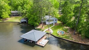 A lakeside property with a covered dock, a house, and a well-maintained lawn.
