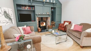A cozy living room with a fireplace, a television, and comfortable seating. - Gilly Skyber (Helston)