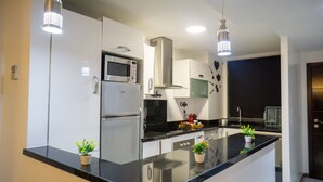 Una cocina moderna con electrodomésticos de acero inoxidable, encimera negra e iluminación colgante.