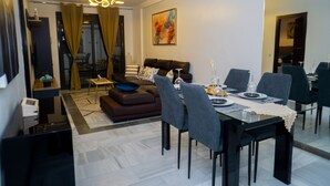 Una sala de estar moderna con sofá, mesa de comedor y sillas. Una escalera conduce a un piso superior.
